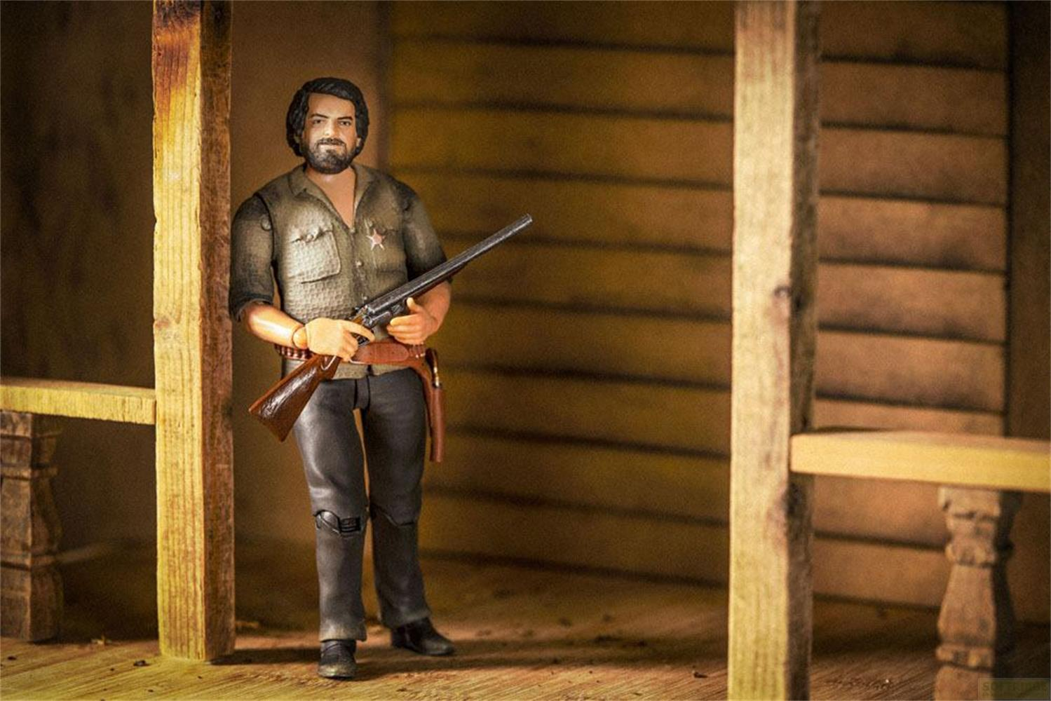 Eine Actionfigur eines Mannes mit Gewehr steht in einem Holzhaus.