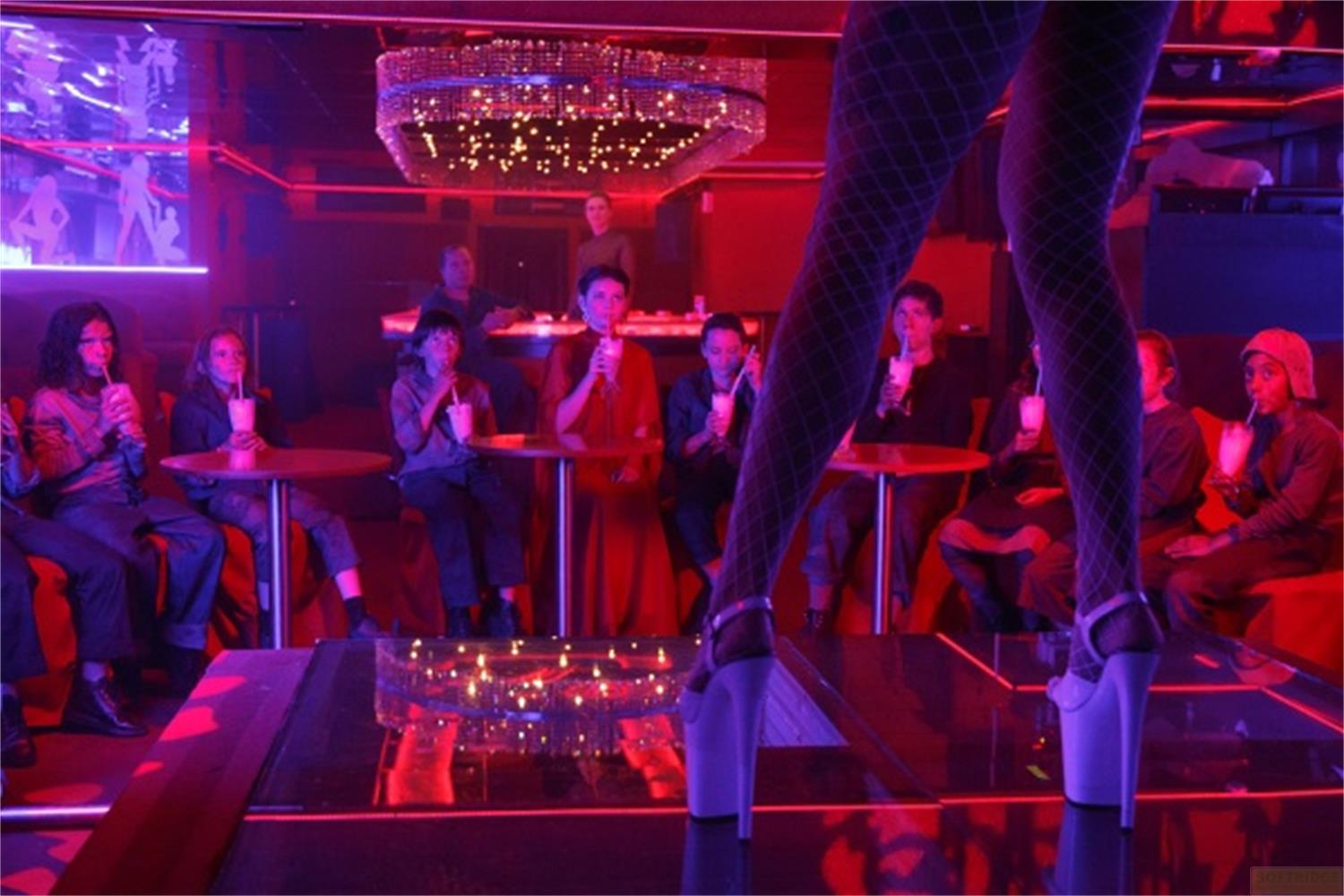 Menschen sitzen an Tischen in einem Nachtclub mit rotem und blauem Licht.