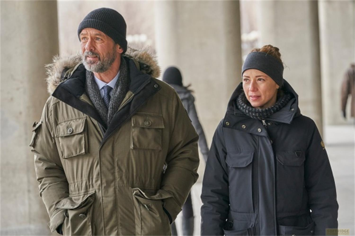 Uomo in parka verde e donna in parka nera camminano fianco a fianco.