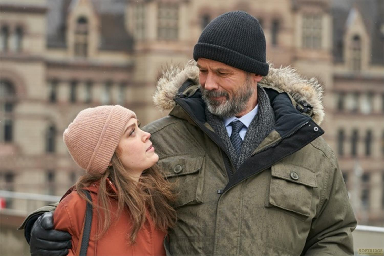 Uomo e donna in cappotti invernali, che si guardano. Sfondo di edificio.