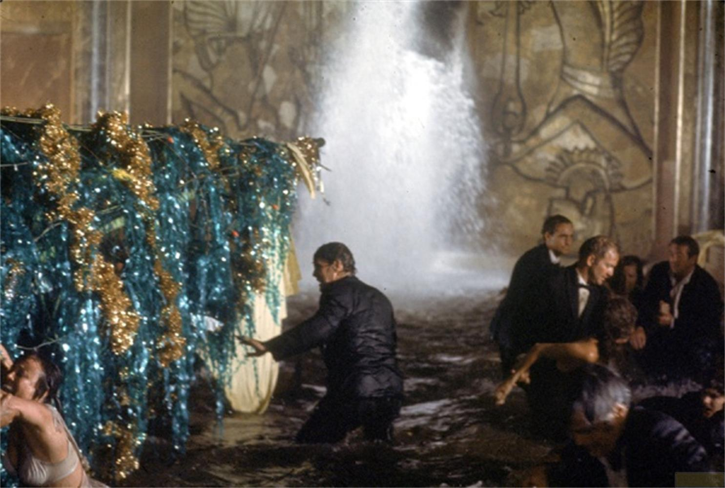 Uomini in abito nell'acqua con una decorazione scintillante e una cascata.