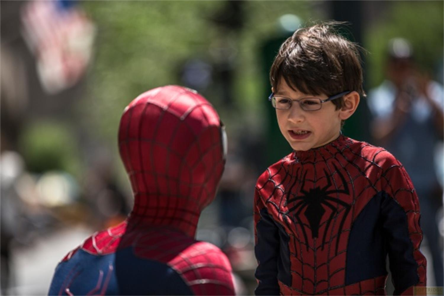 Ein Kind in Spiderman-Kostüm spricht mit einer Person im Spiderman-Kostüm.