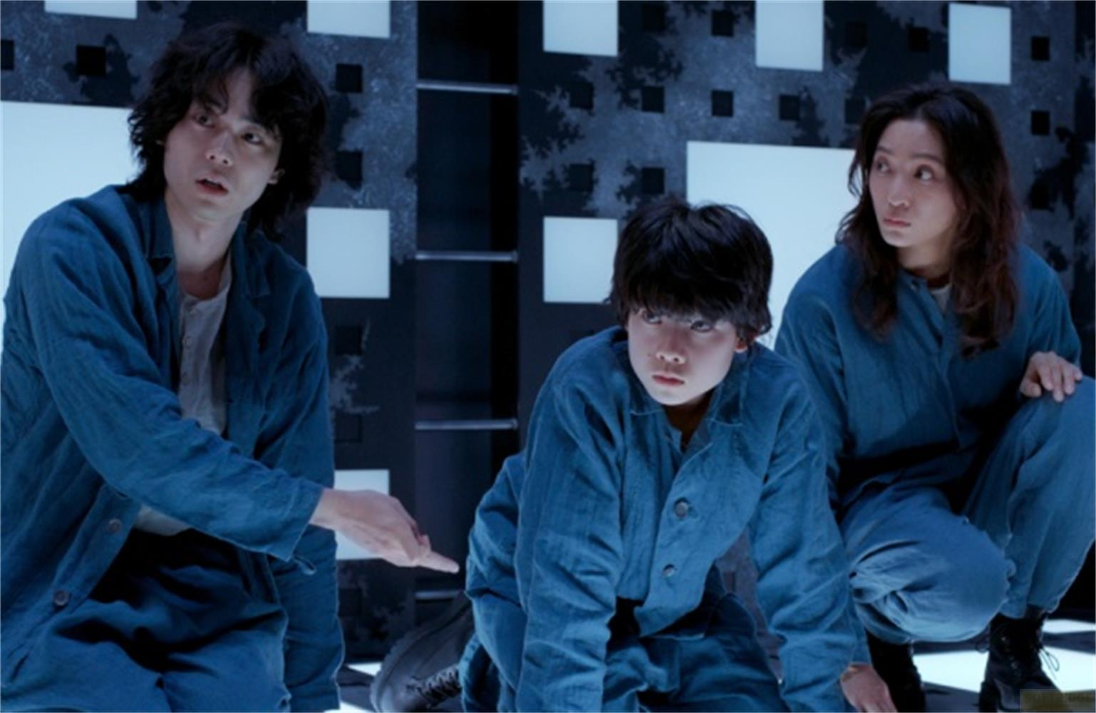 Tre persone in abiti blu guardano a sinistra. Uno indica con il dito.