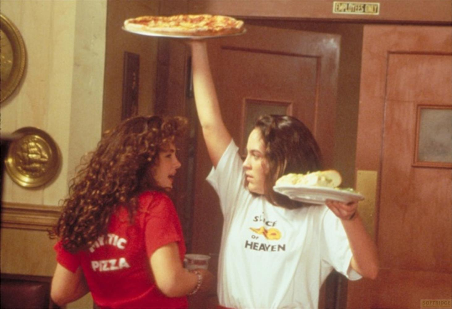 Due donne in un ristorante, una tiene una pizza e l'altra un panino.