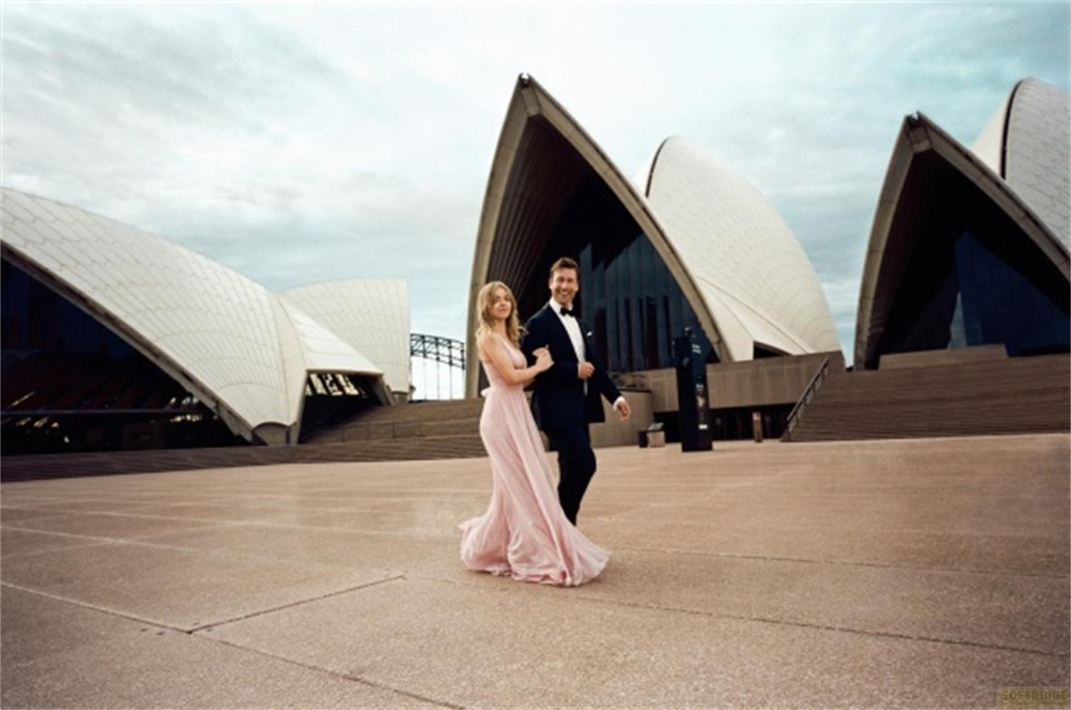 Una coppia in abiti eleganti di fronte al Teatro dell'Opera di Sydney.