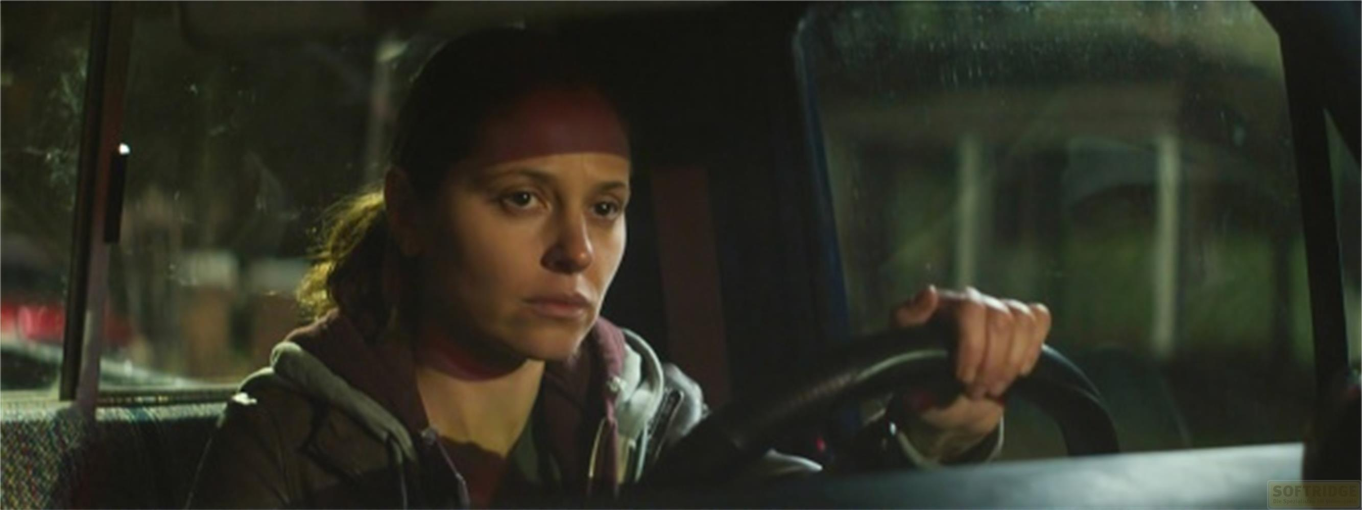 Eine Frau fährt nachts in einem Auto, ihr Gesicht ist nachdenklich.