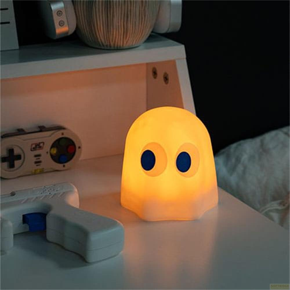 Een gloeiende spooklamp met blauwe ogen staat op een nachtkastje naast een controller.
