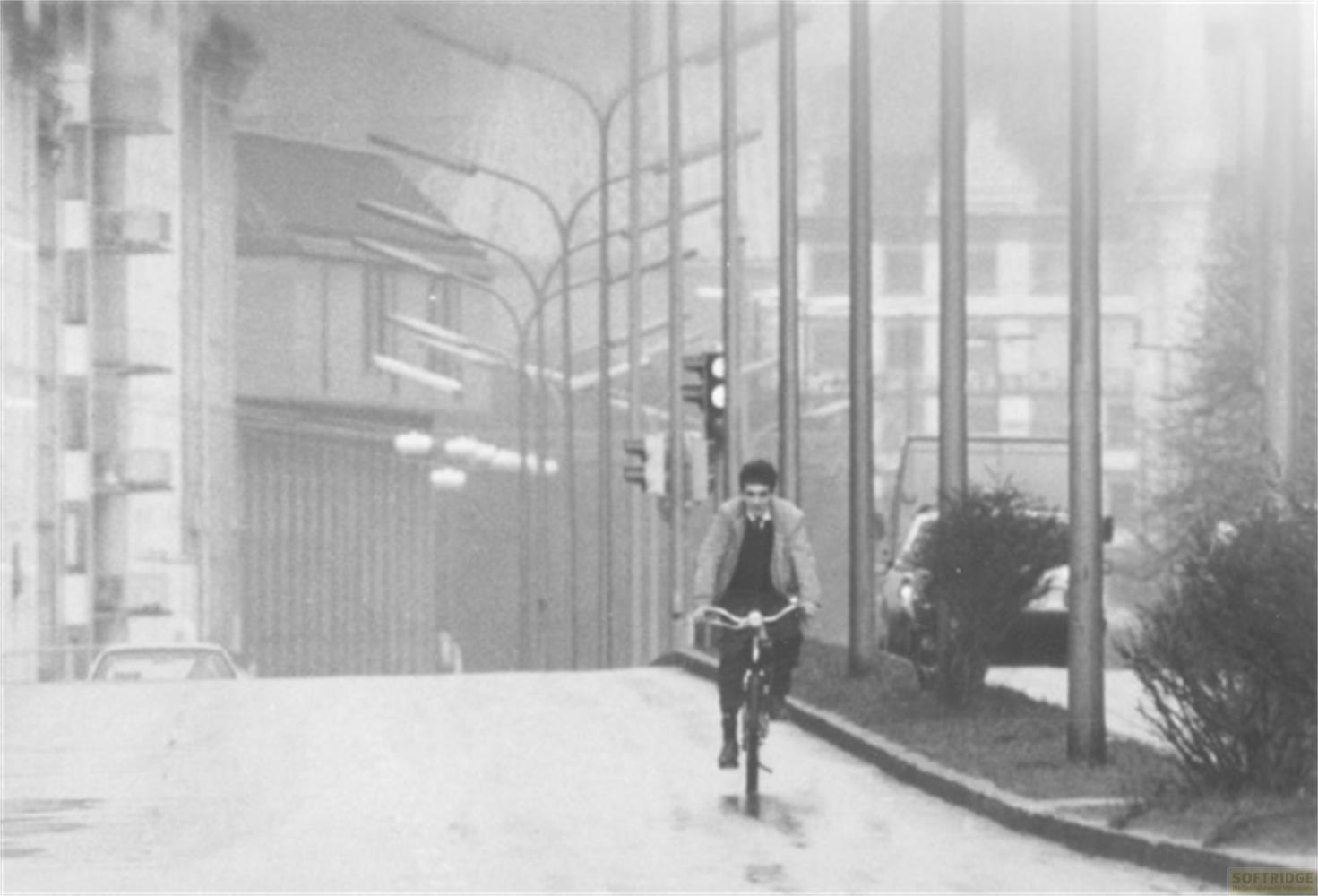 Un uomo in bicicletta per strada con edifici e lampioni.