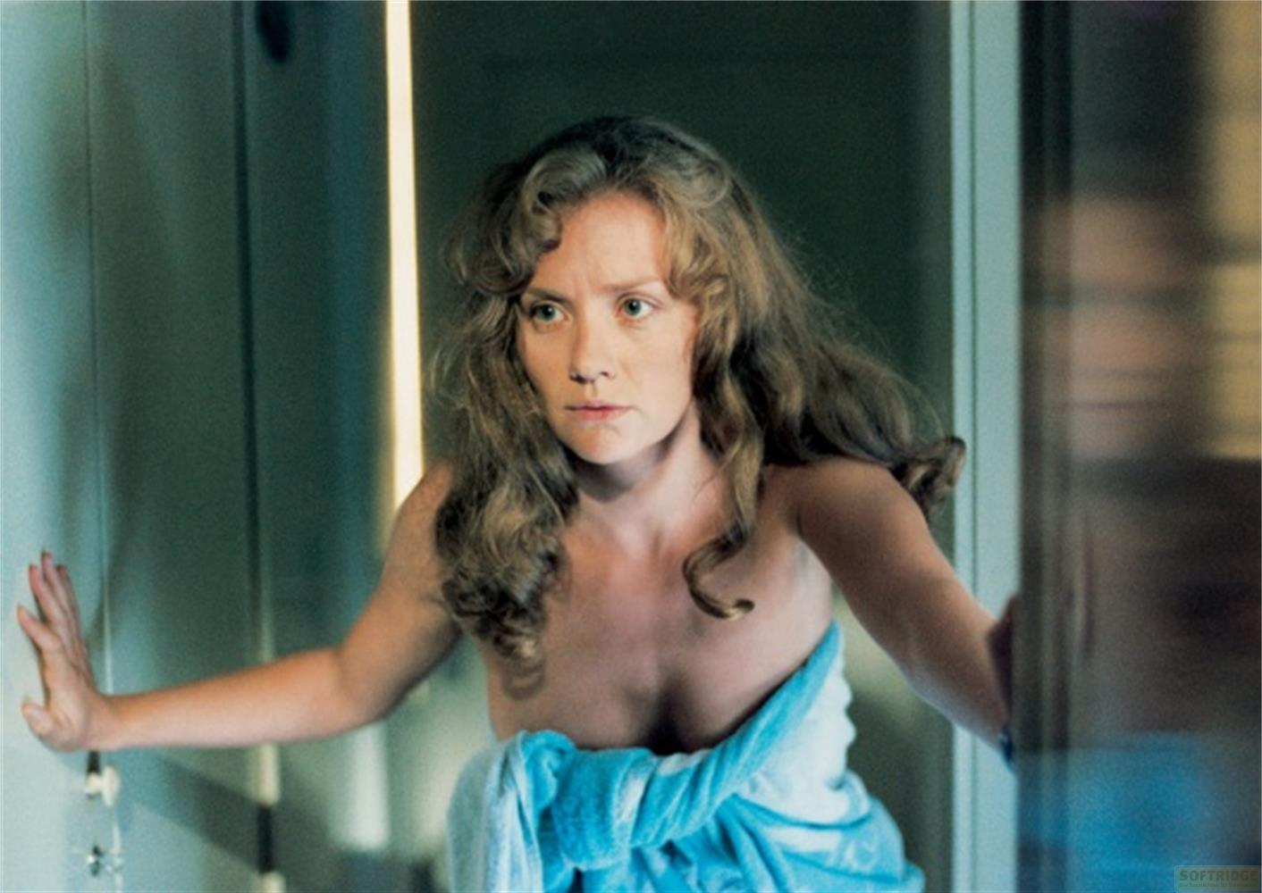 Una donna con lunghi capelli mossi è avvolta in un asciugamano blu.