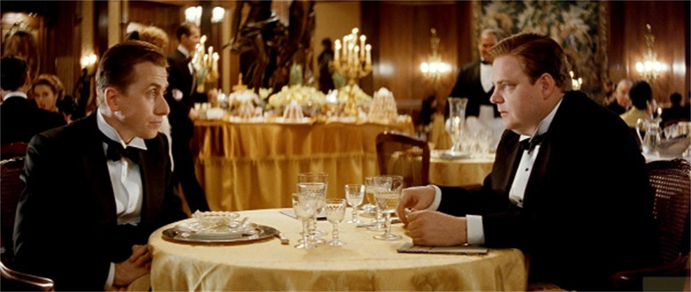Due uomini in smoking seduti a un tavolo in un'elegante sala da pranzo.