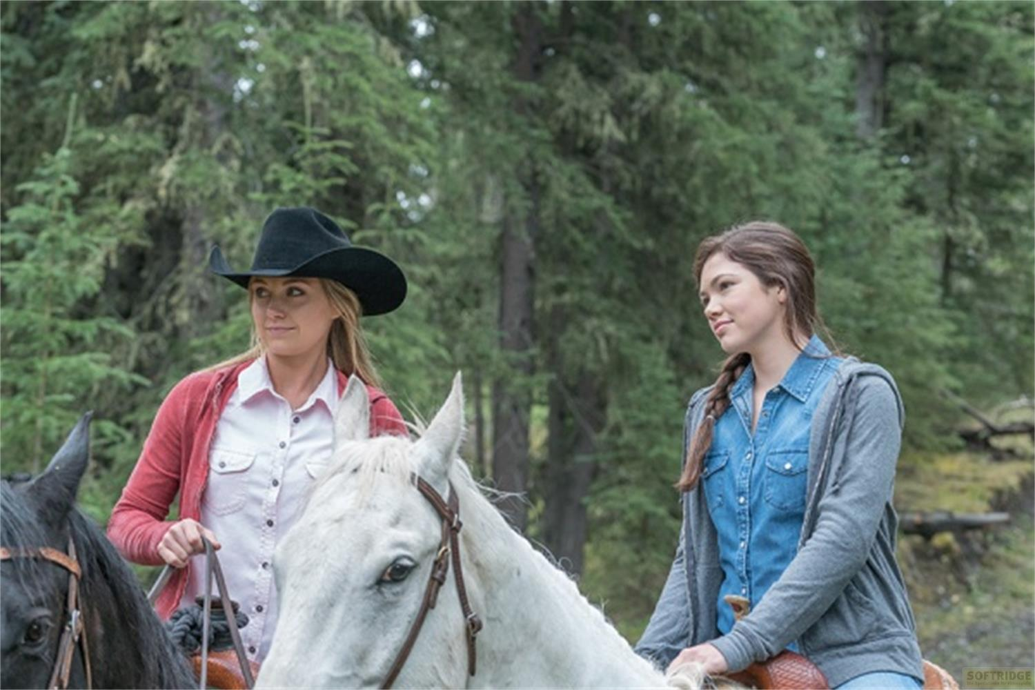 Due donne a cavallo in una foresta, una indossa un cappello da cowboy nero.
