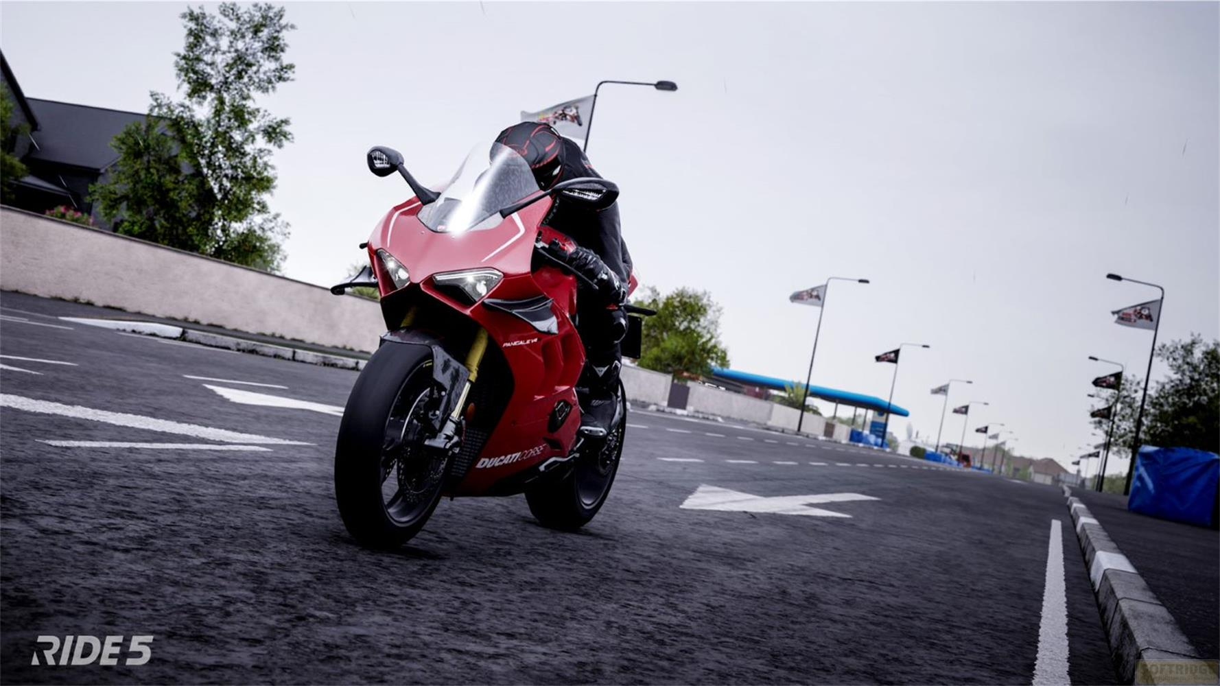 Rotes Motorrad auf einer Rennstrecke mit Fahnen und Bäumen.