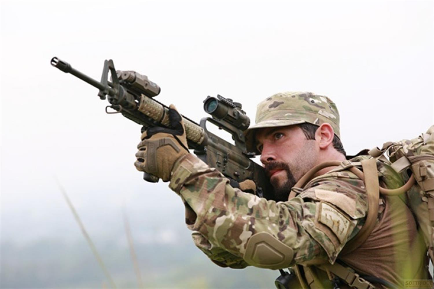 Soldat en tenue de camouflage vise un fusil, ciel couvert.