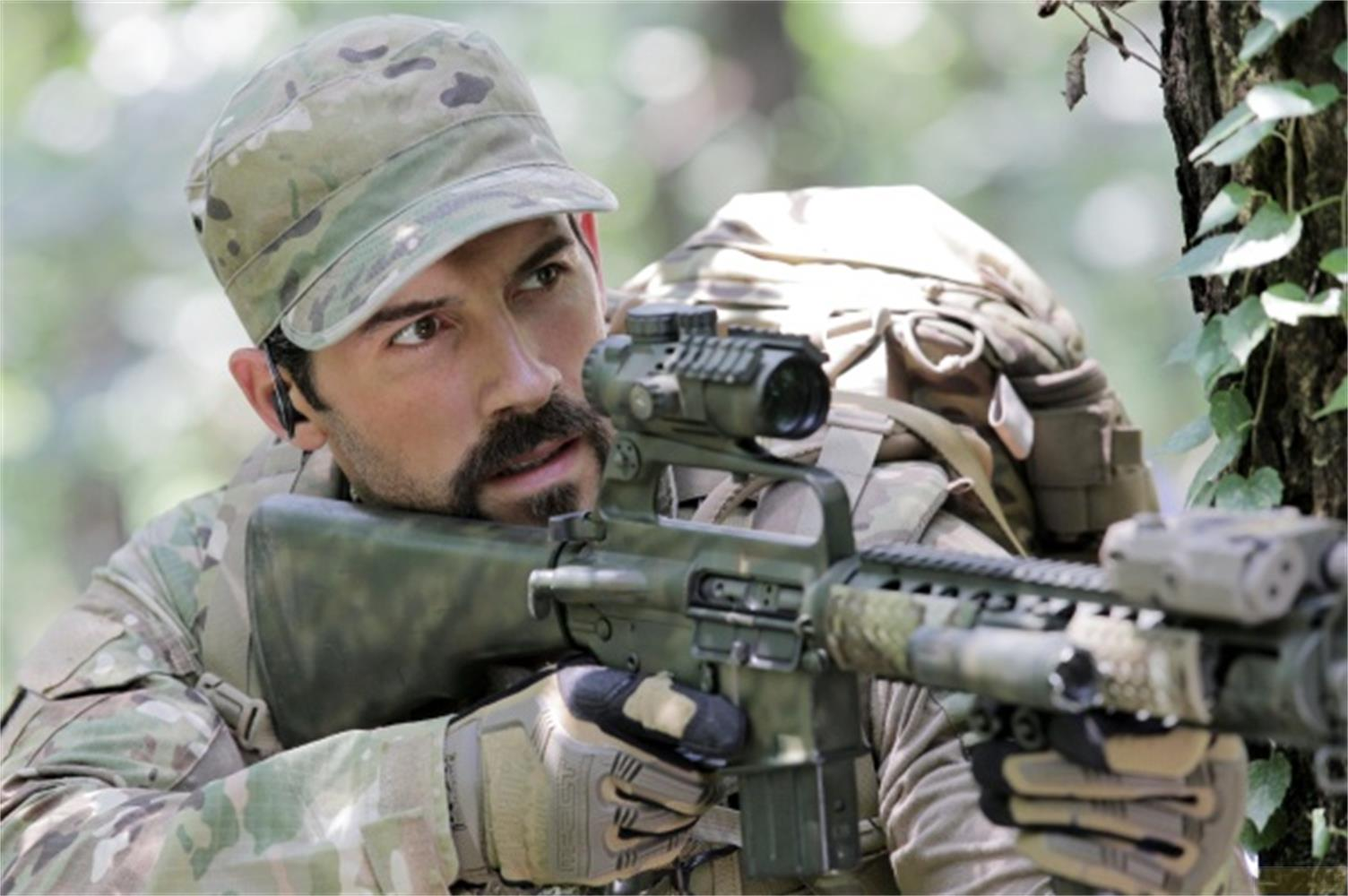 Un homme en tenue de camouflage avec un fusil et un sac à dos dans les bois.