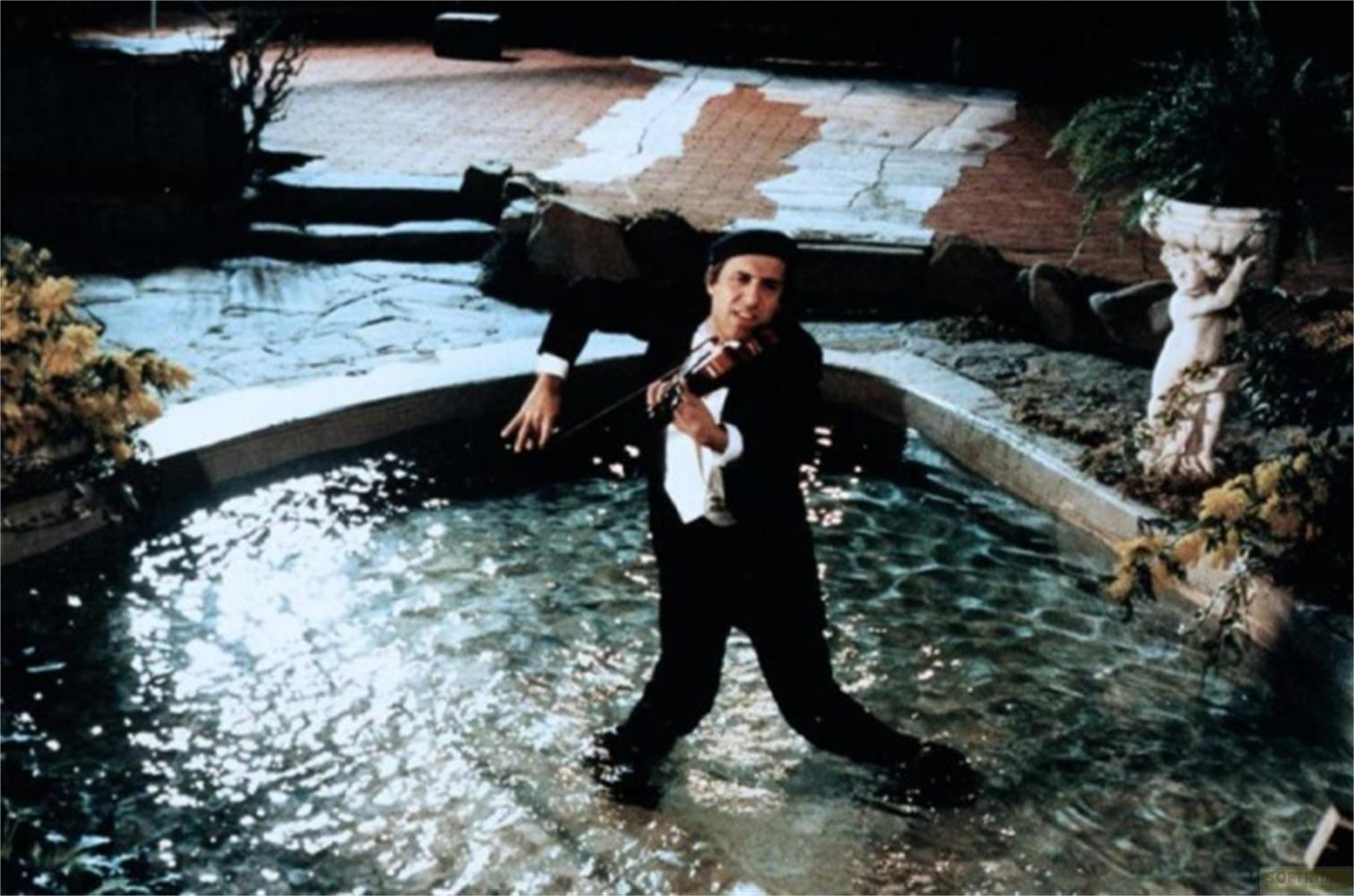 Un uomo in nero suona il violino in una fontana.