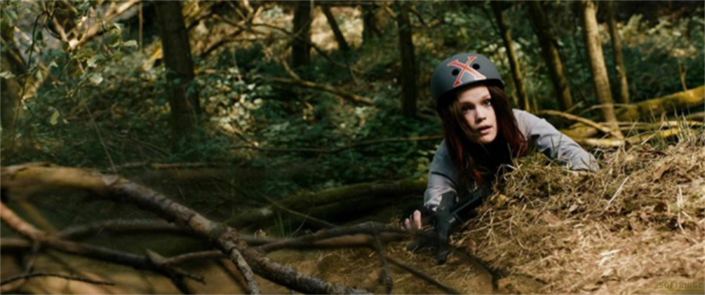 Una ragazza con casco striscia sull'erba secca in una foresta.
