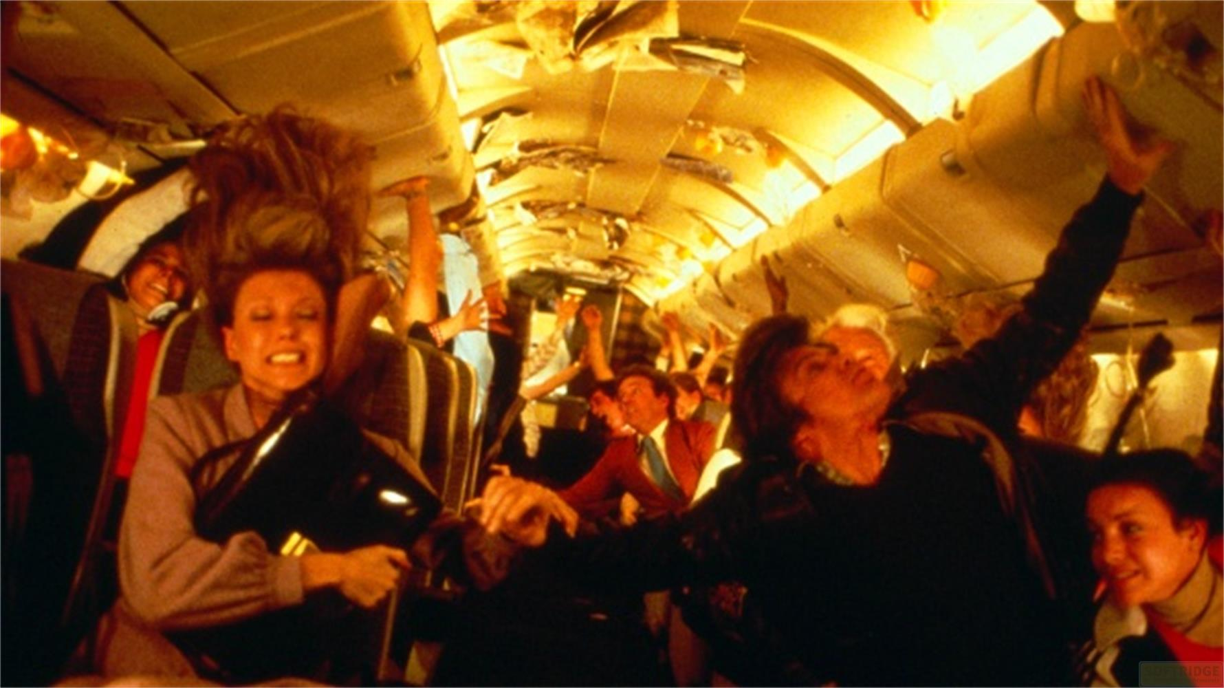 Passeggeri in preda al panico su un volo aereo, aggrappati ai sedili e ai vani portaoggetti.