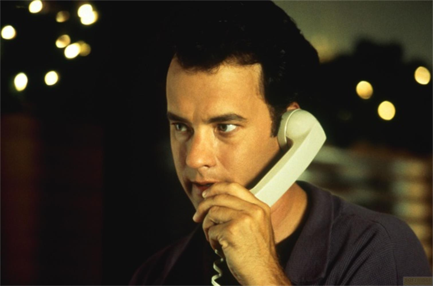 Homme tenant un combiné de téléphone à son oreille, fond sombre avec lumières.