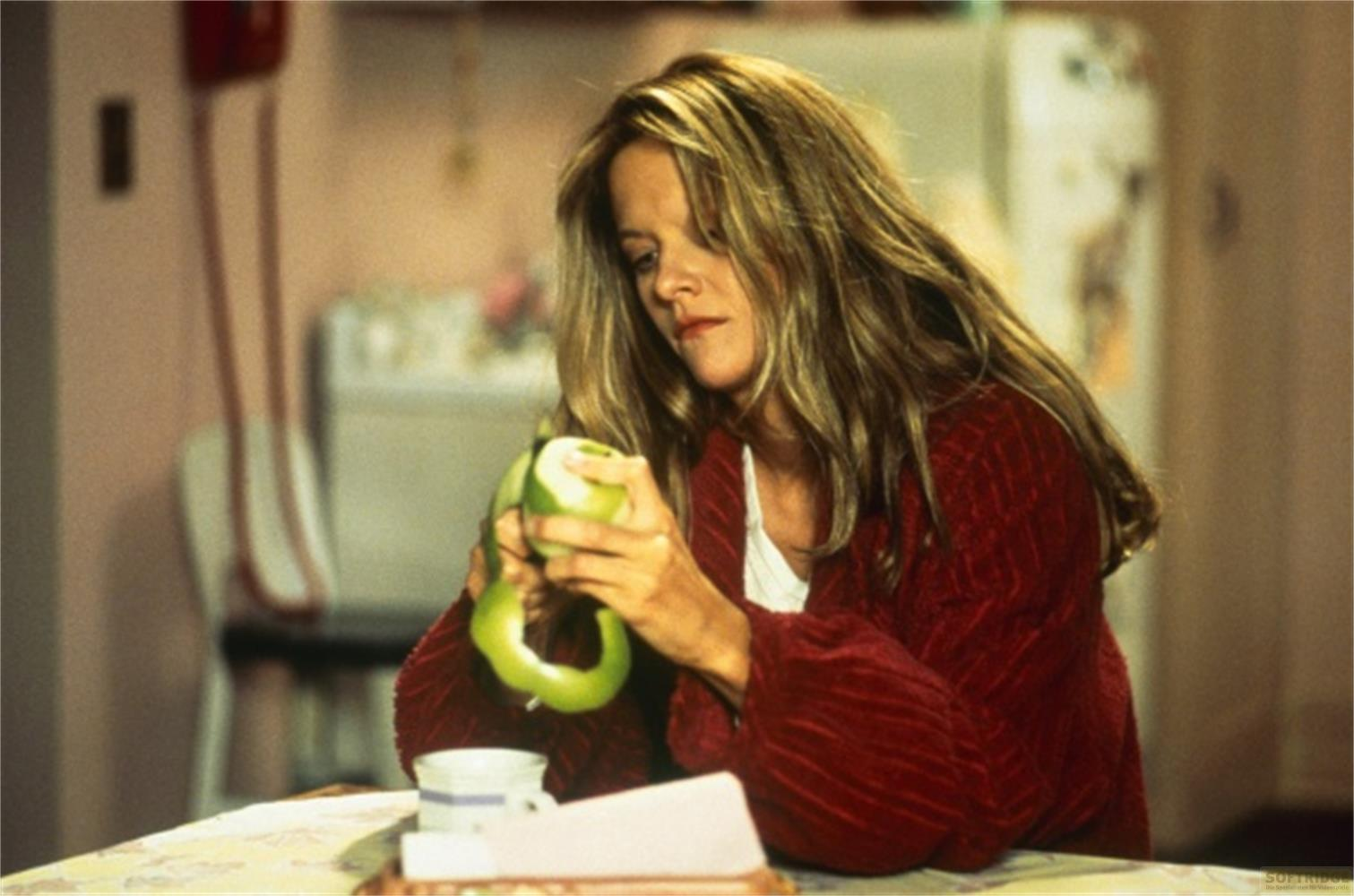 Une femme pèle une pomme verte dans un cadre domestique.