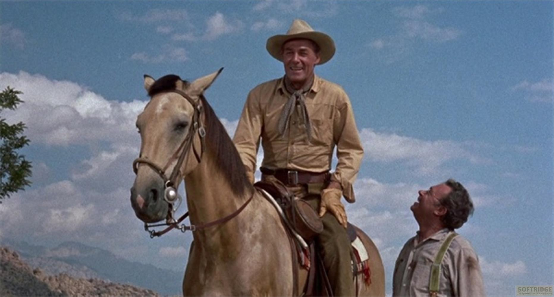 Cowboy sorridente a cavallo guarda uomo con bretelle contro cielo blu.