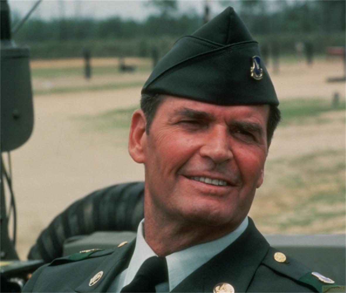 Un uomo in uniforme militare e cappello sorride alla telecamera.