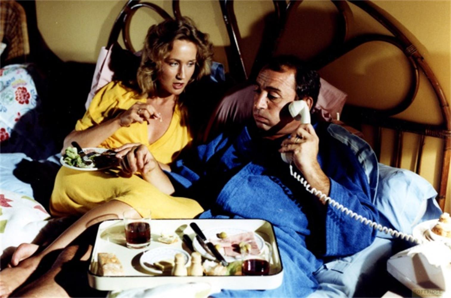 Una donna in giallo mangia insalata, un uomo in vestaglia blu al telefono.