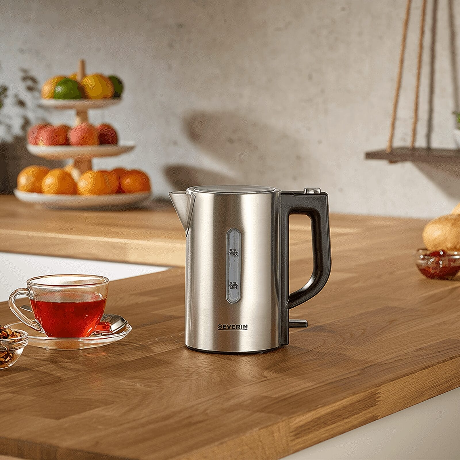 Czajnik ze stali nierdzewnej z czarnym uchwytem, obok filiżanki herbaty.