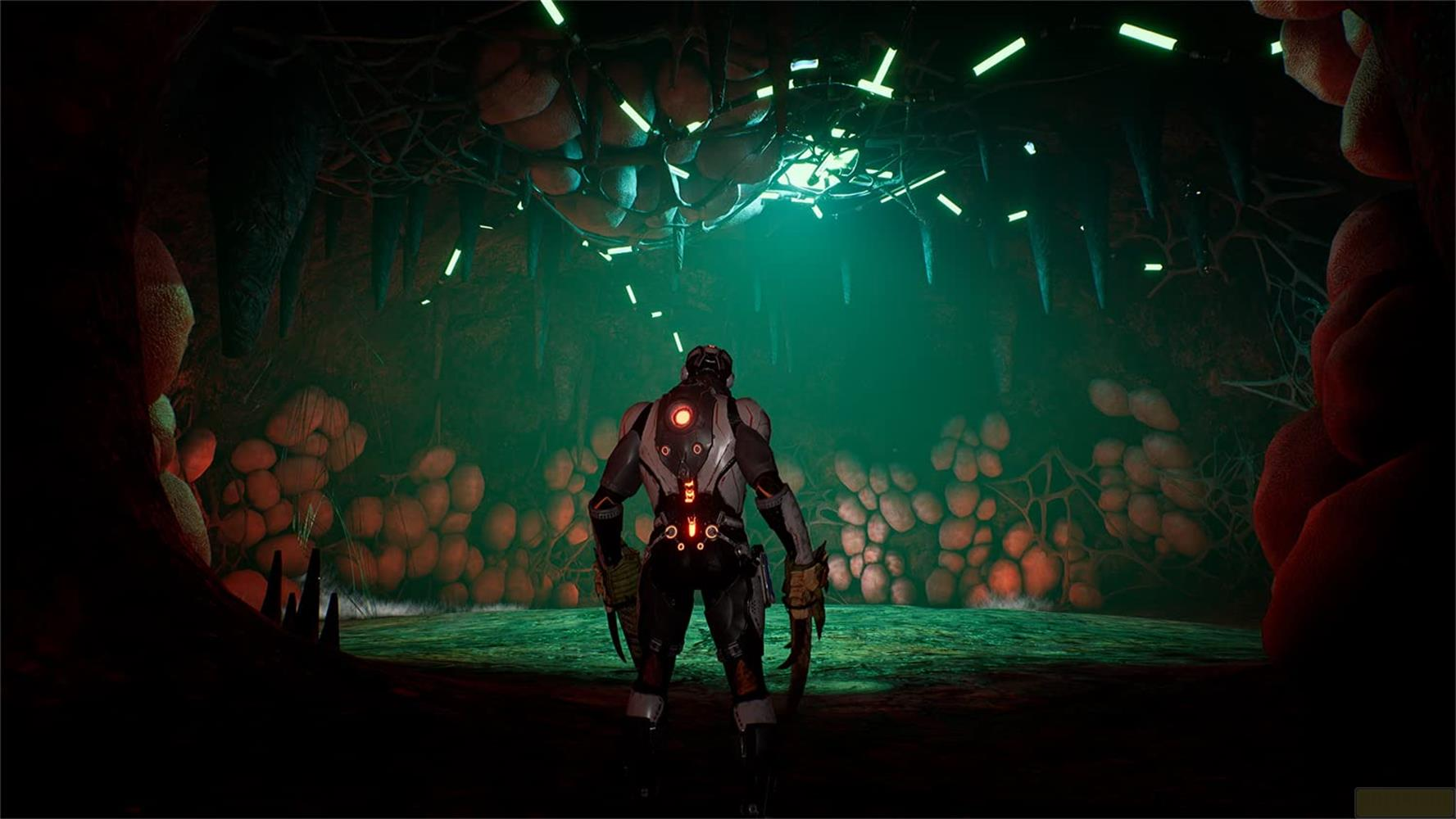 Eine einsame Figur in futuristischer Rüstung steht in einer Höhle mit leuchtend grünen Lichtern.