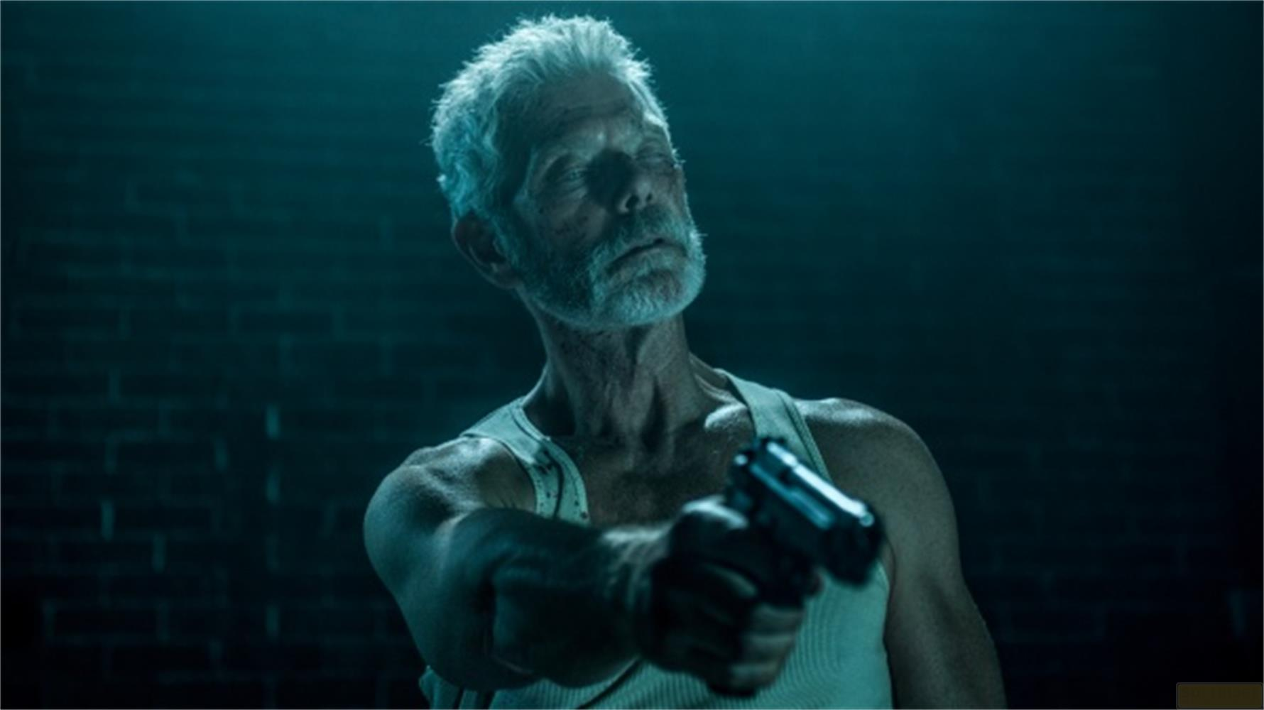 Un homme âgé aux cheveux gris vise un pistolet.