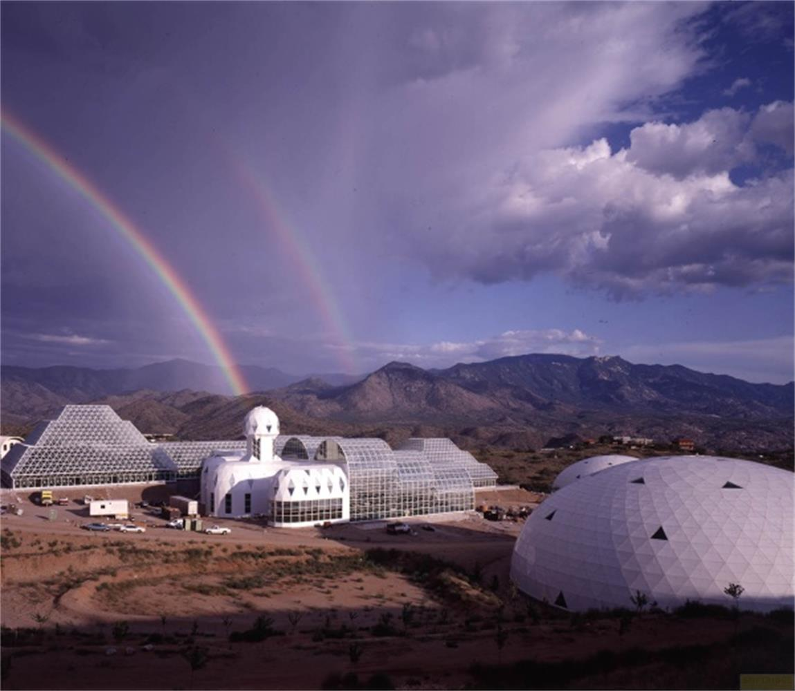 Biosfera 2 con doppio arcobaleno e montagne sullo sfondo.