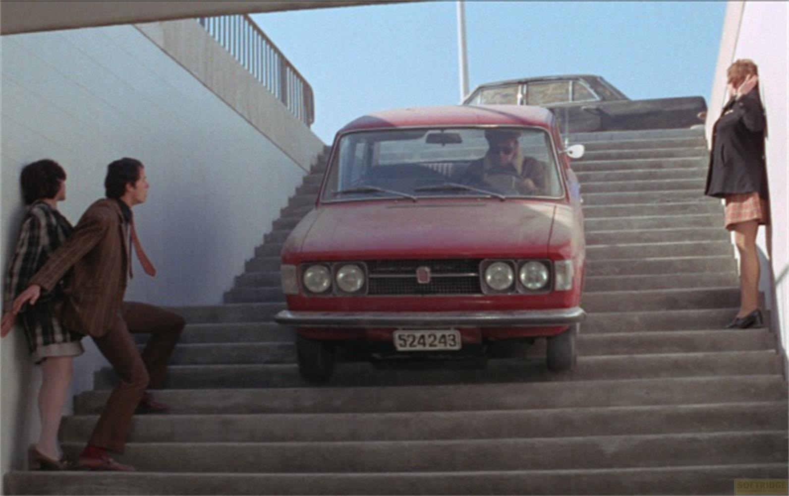 Une voiture rouge monte des escaliers avec des gens sur les marches.