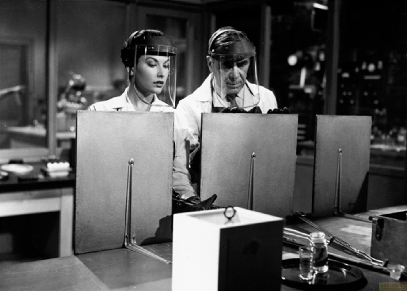 Homme et femme portant des visières dans un laboratoire, devant des écrans.