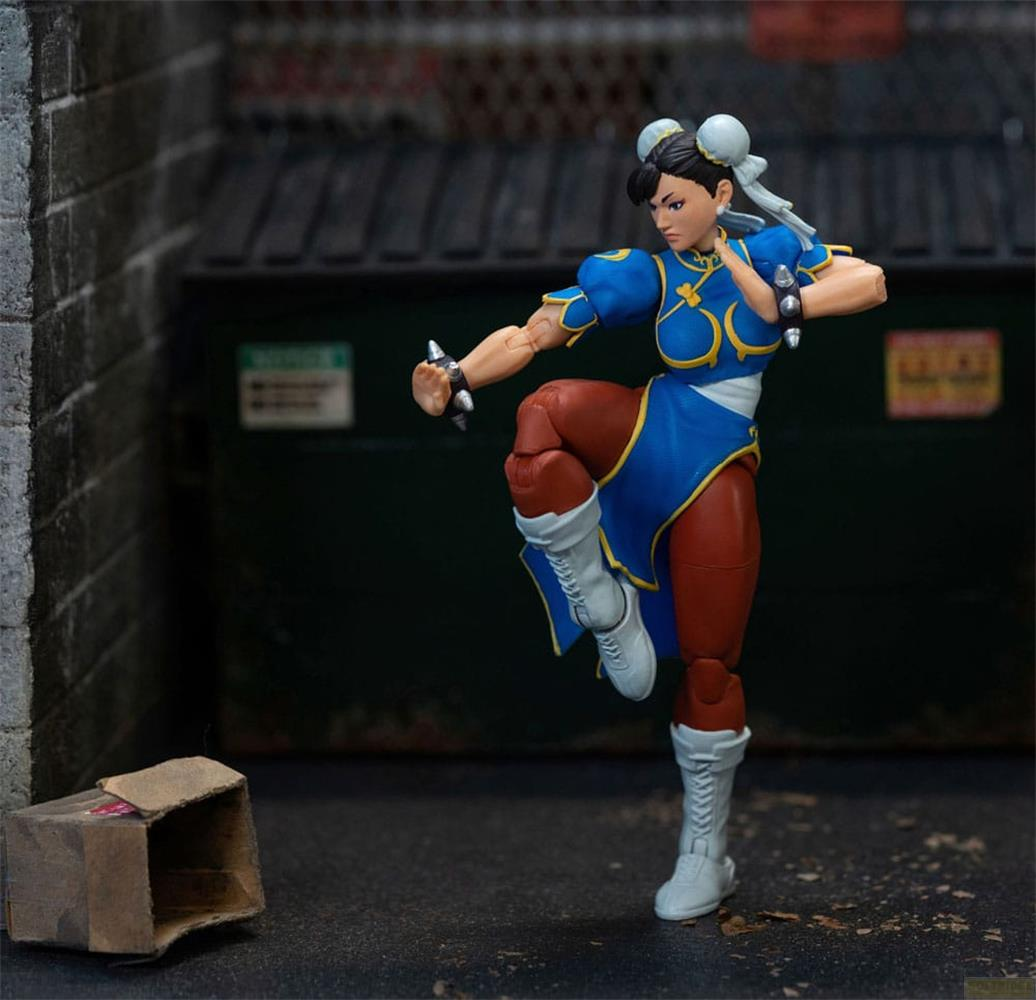 Figurka akcji Chun-Li w niebieskim stroju w pozie bojowej przed śmietnikami.