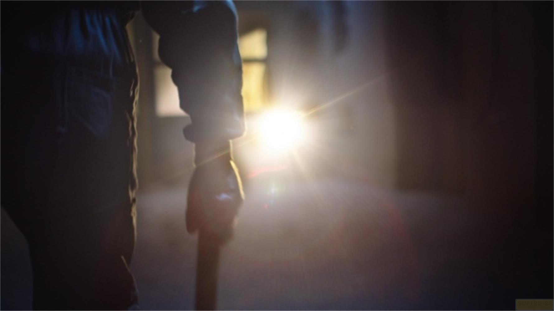 Persona con bastone davanti a luce intensa in stanza buia.