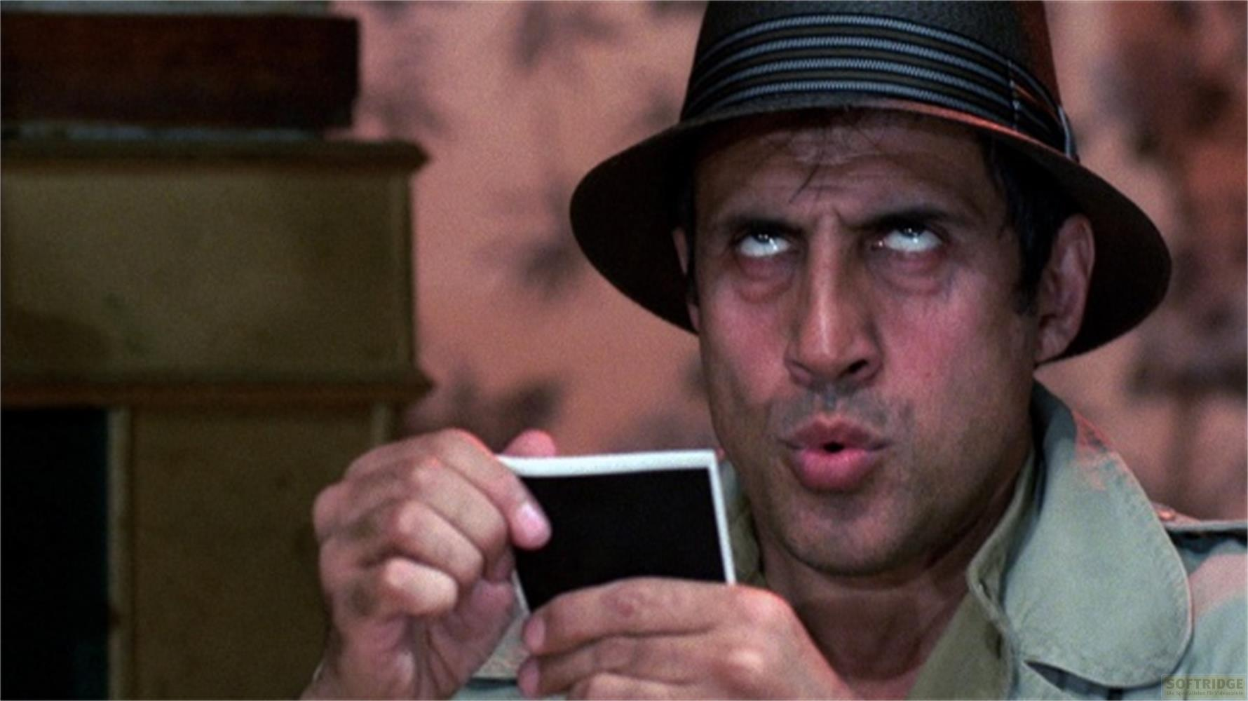 Uomo con cappello tiene una foto vuota, guarda in alto.