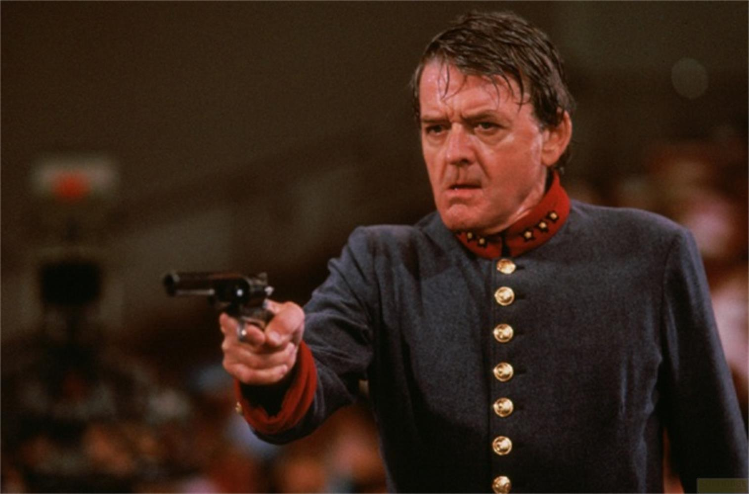 Uomo in uniforme con pistola, che punta in avanti.