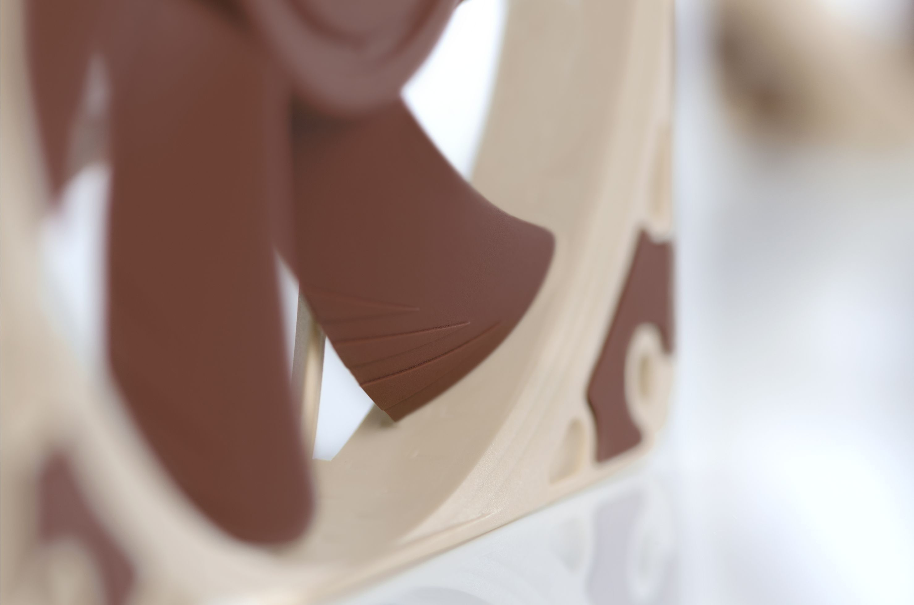 Zbliżenie brązowego łopatki wentylatora z rowkami, zamontowanej na beżowej ramie.