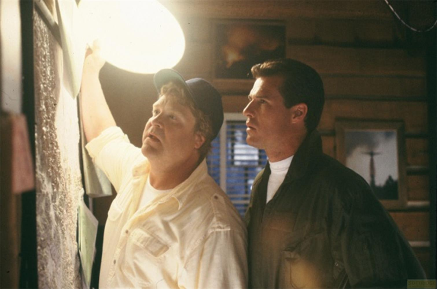 Uomo con cappellino illumina muro, uomo accanto guarda.