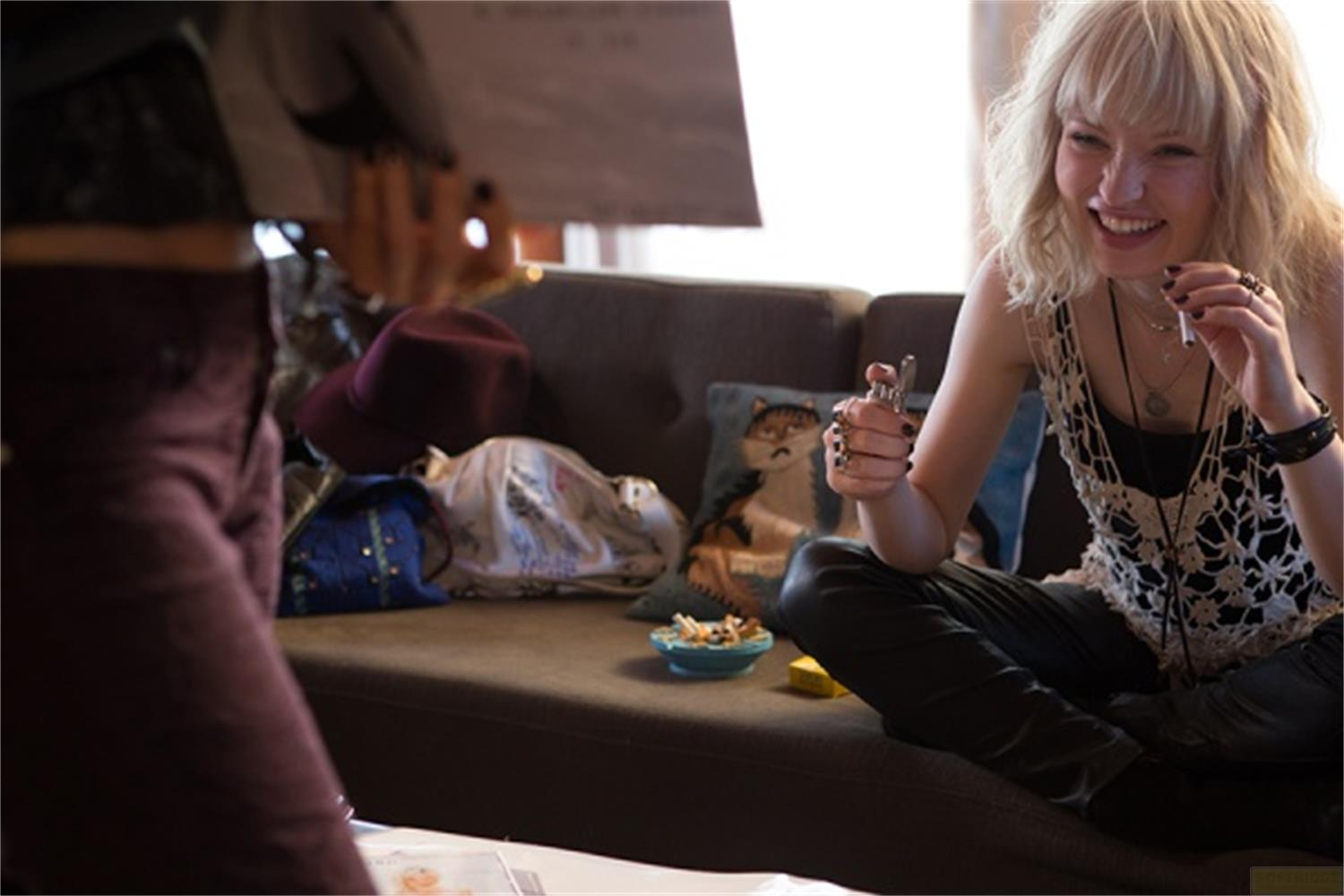 Une femme rit, tenant un briquet. Une cigarette à la bouche.