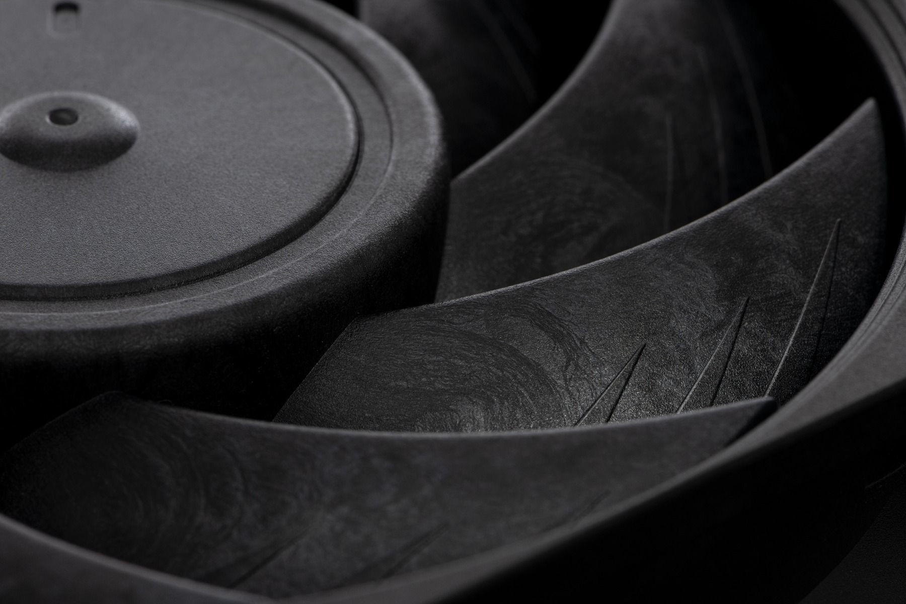 Zbliżenie czarnego wentylatora z zakrzywionymi łopatkami i okrągłym piastą.