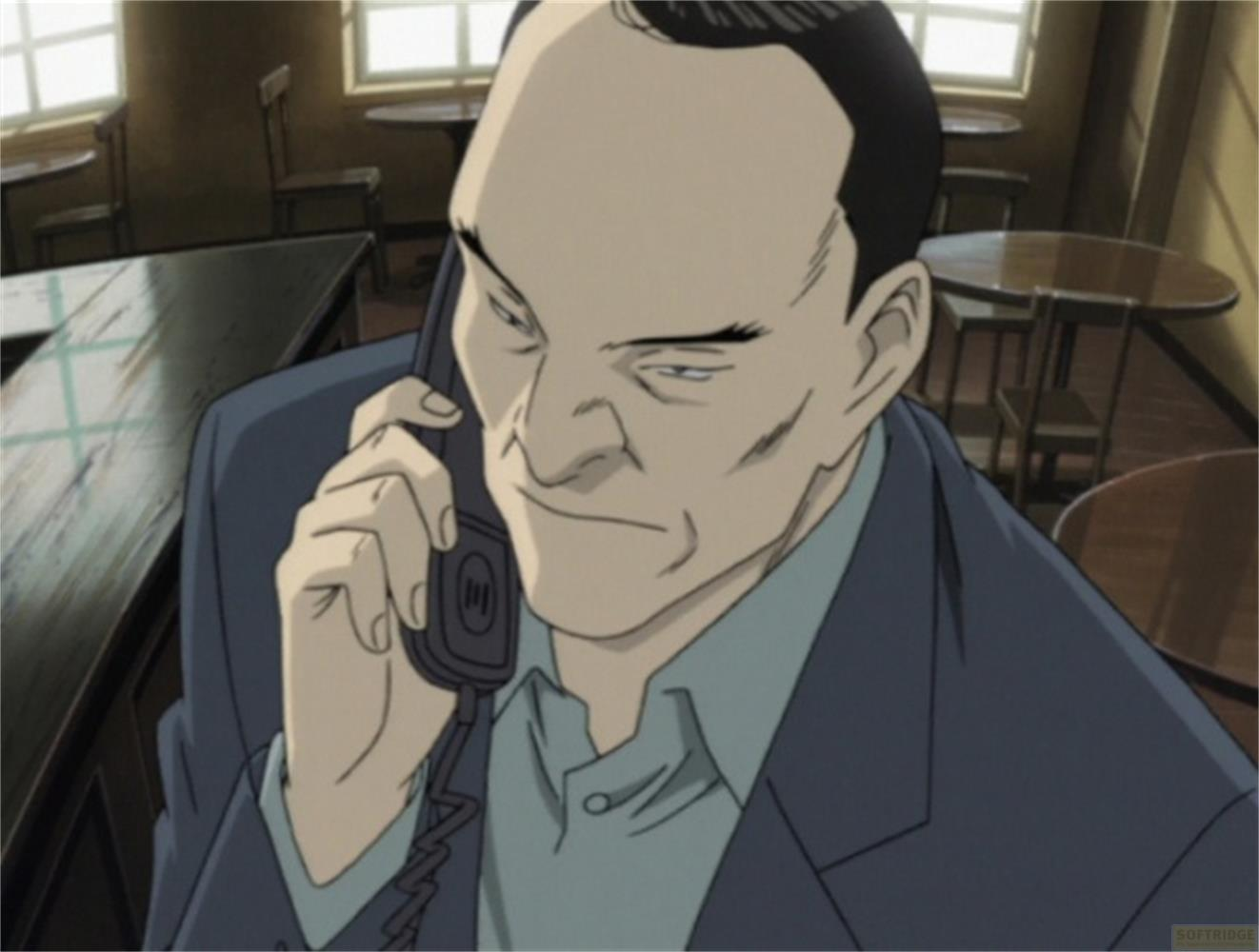 Uomo in abito blu parla al telefono in un caffè con tavoli rotondi.