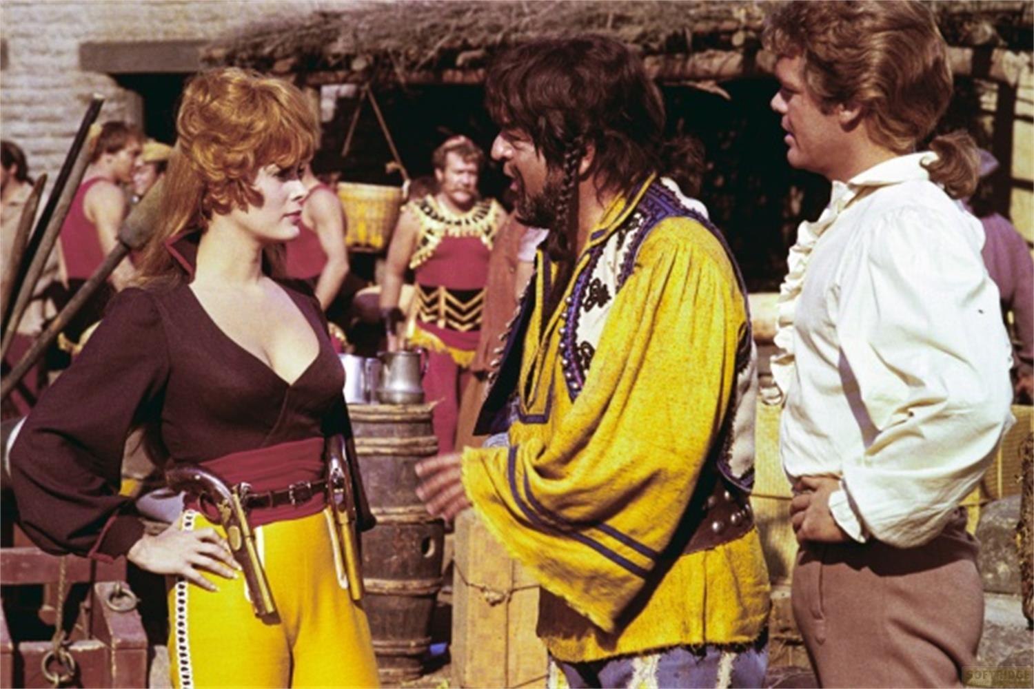 Una donna in giallo e un uomo in giallo parlano davanti ad altri uomini.