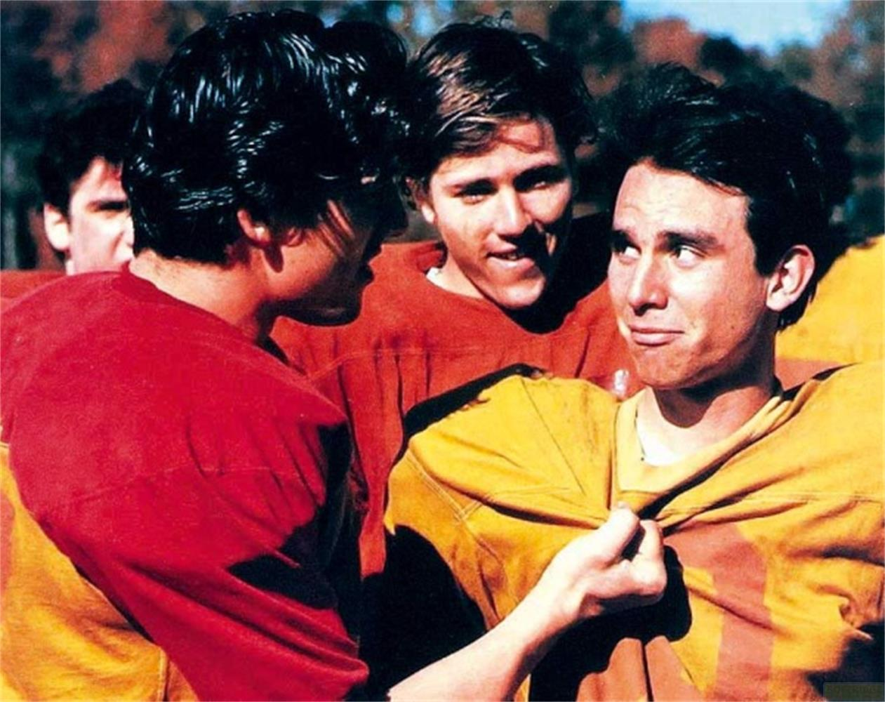 Tre giovani in maglie da football, due parlano, uno sorride.