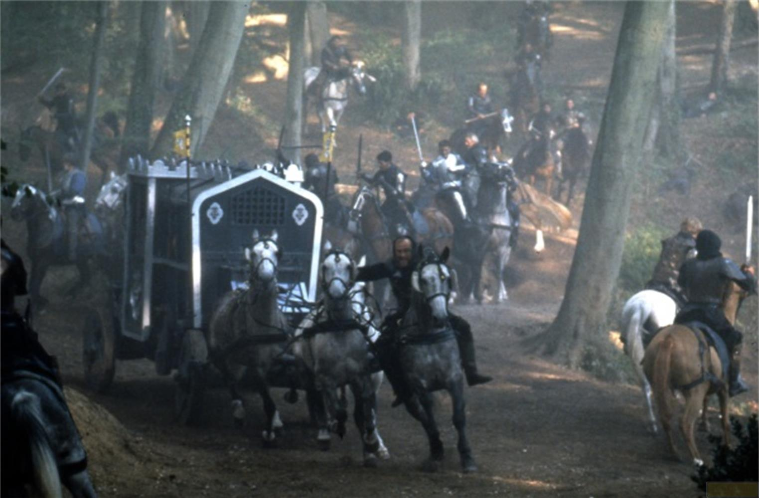 Una carrozza medievale trainata da cavalli in una foresta, con cavalieri intorno.