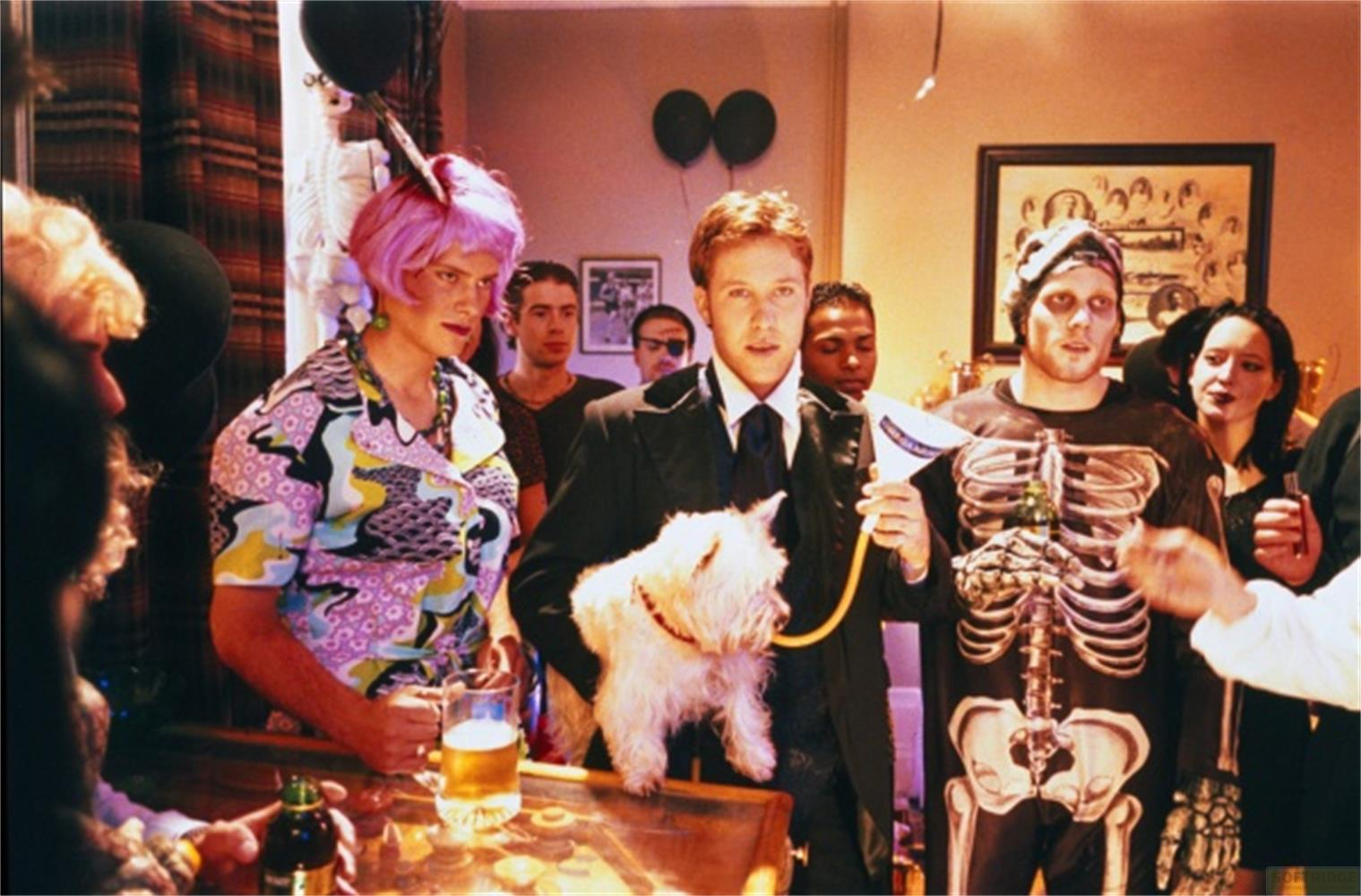 Persone in costume a una festa; una persona indossa un costume da scheletro con un cane.