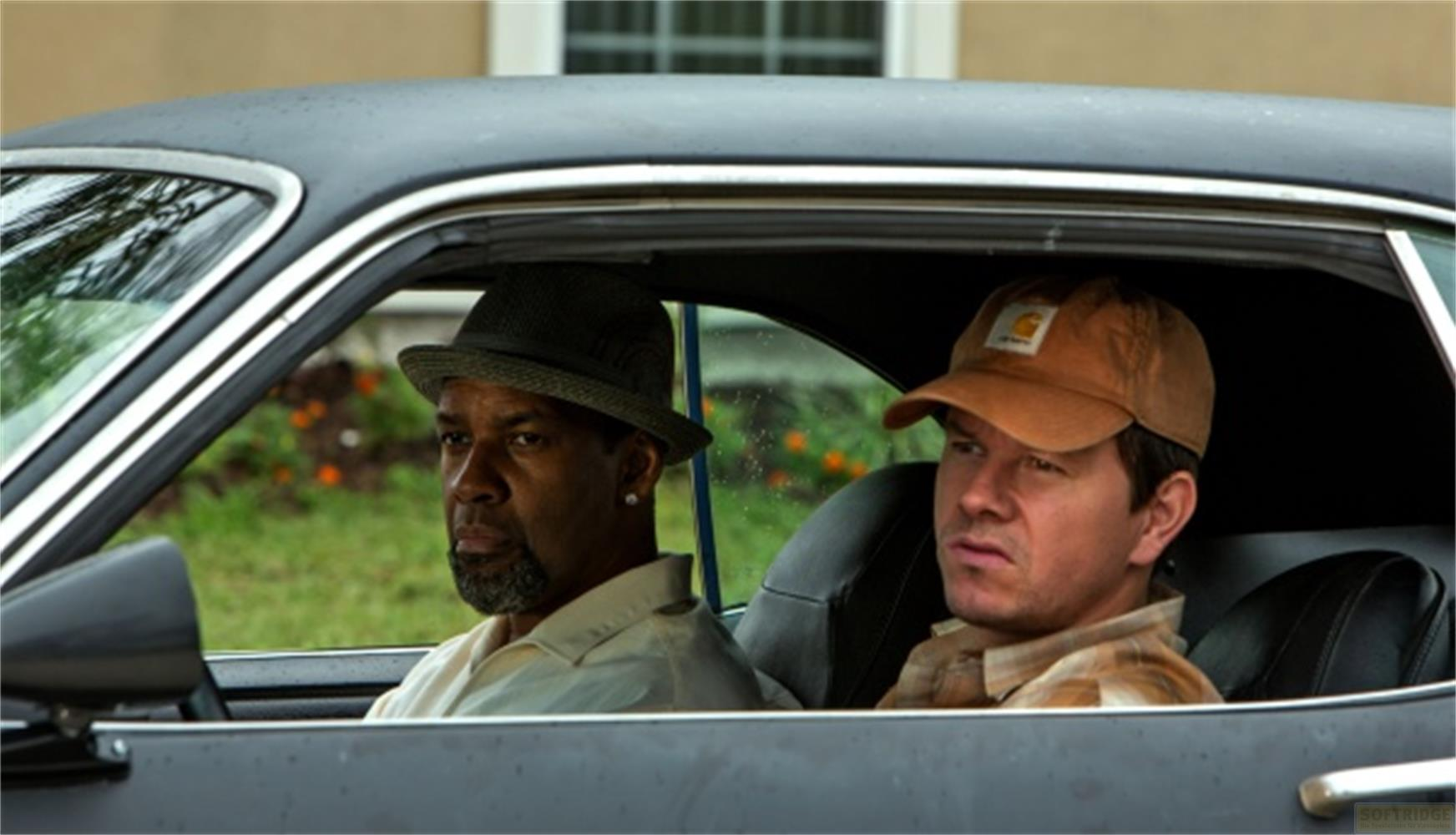 Deux hommes sont assis dans une voiture. L'un porte un chapeau, l'autre une casquette.
