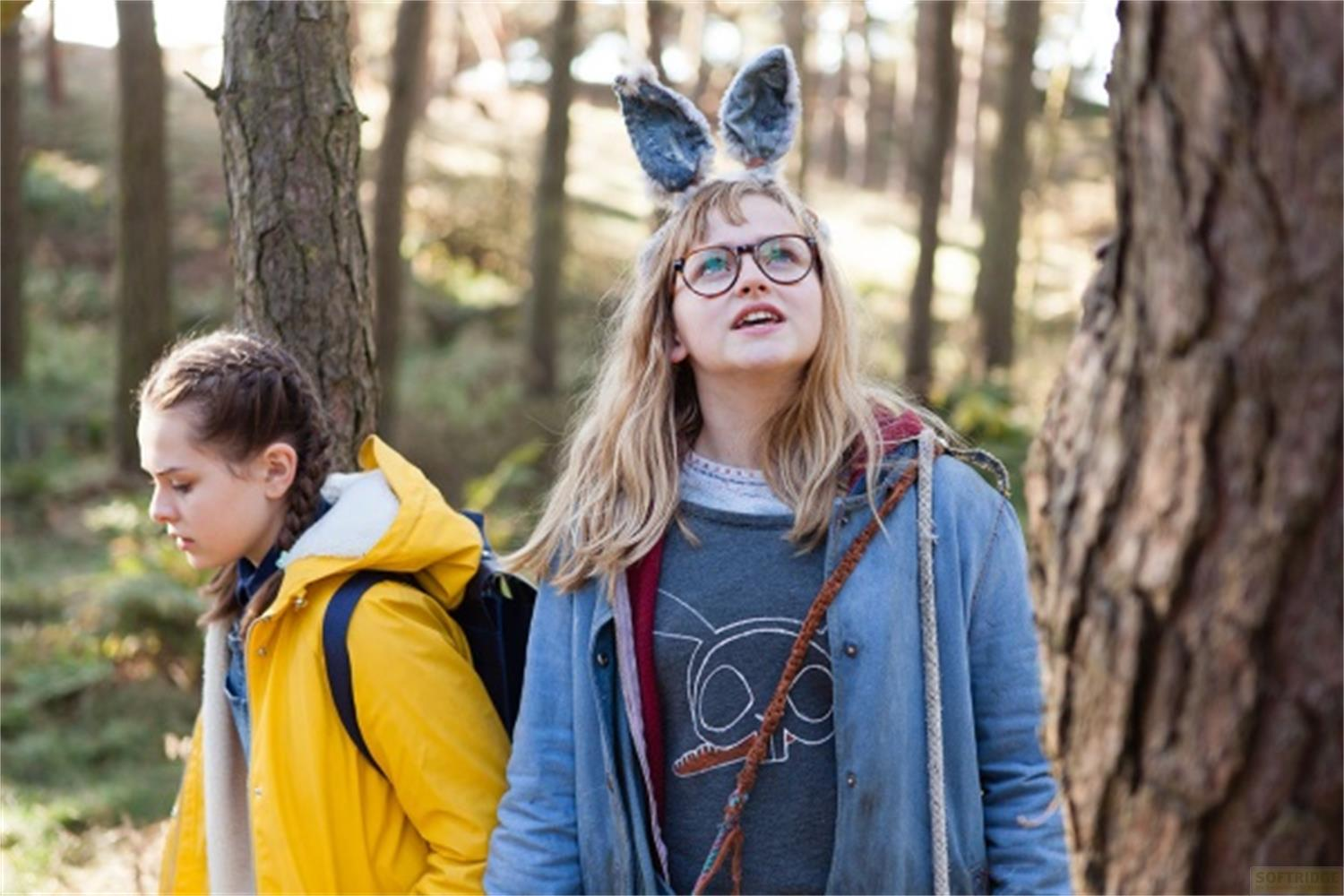 Due ragazze con zaini in un bosco. Una indossa orecchie da coniglio e occhiali.