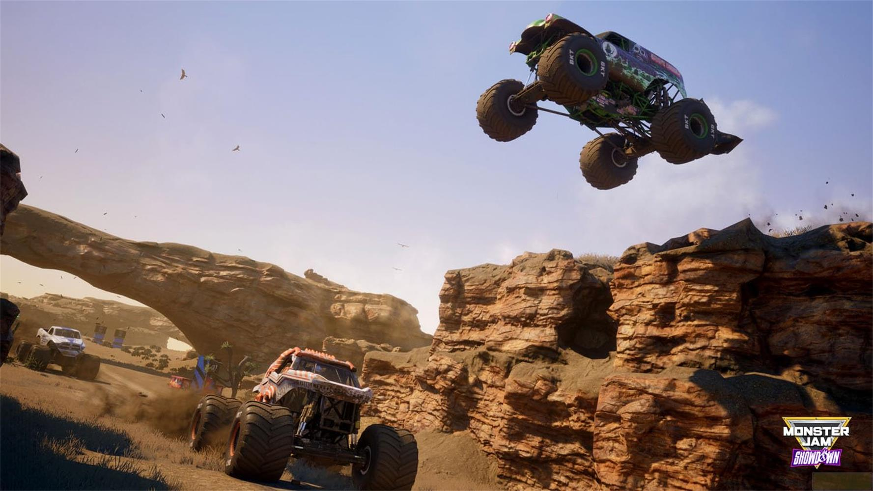 Ein grüner Monster-Truck springt, während ein orange-weißer Truck fährt. Wüstenlandschaft.