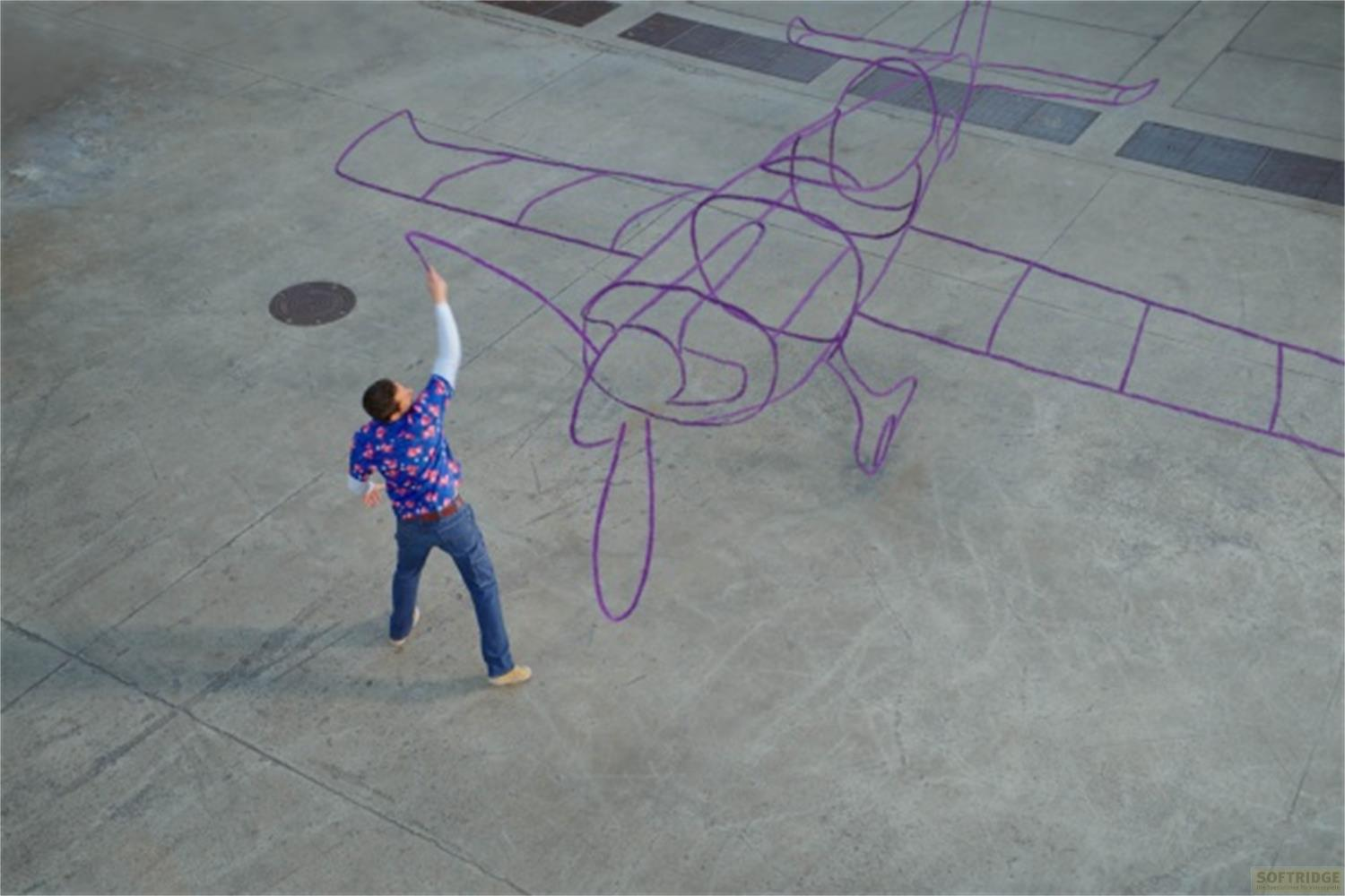 Un uomo disegna il contorno viola di un aereo sul cemento.