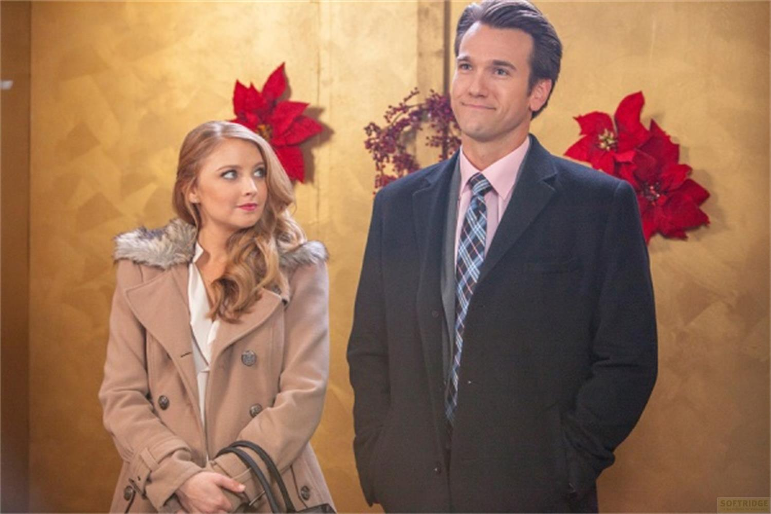 Uomo e donna davanti a muro dorato con stelle di Natale rosse.